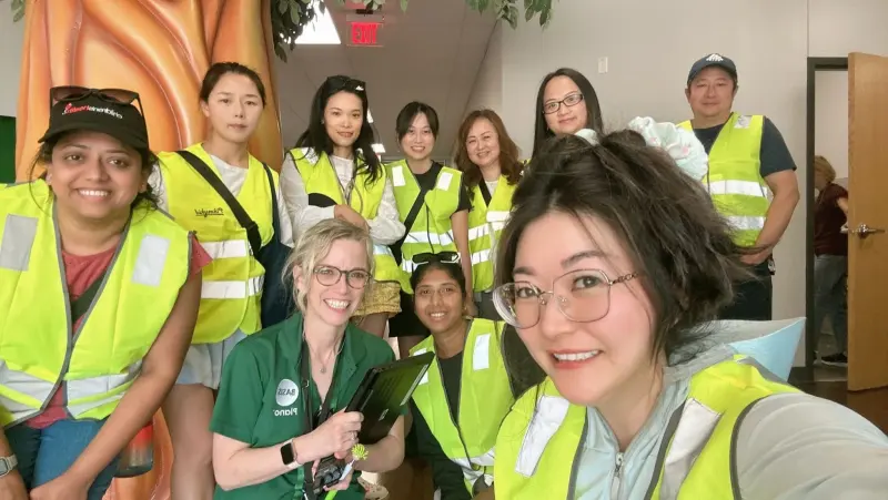 A selfie of ten carline volunteers in hi-vis vests crowded into the lobby beside the tree sculpture