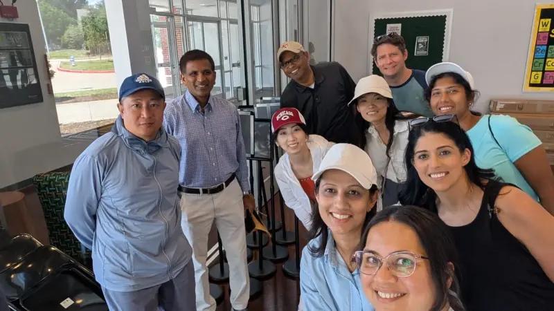 Eleven volunteers gathered in the lobby in caps and sun hats after a morning carline shift