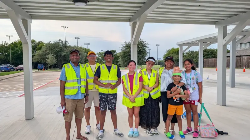 Eight volunteers and two children lined up under the drop-off canopy in hi-vis vests, the empty car park stretching behind