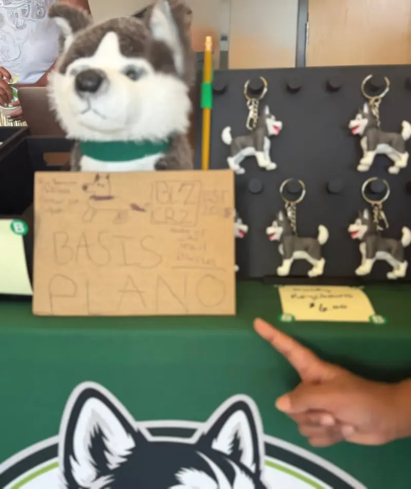 A child pointing at the husky keychains pegged on the display board, beside a hand-drawn sign for the stall
