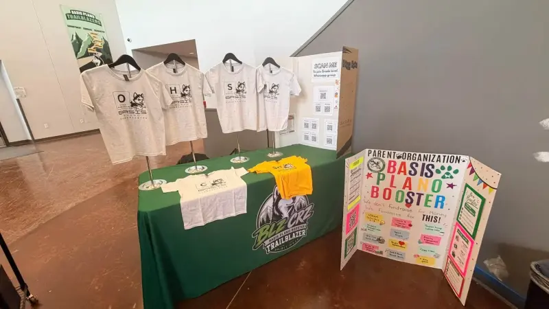 The spirit wear table set up in the lobby, four element shirts on stands behind it and the Booster display board alongside