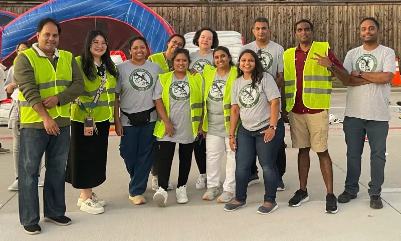 Twelve volunteers in Booster shirts and hi-vis vests lined up in front of an inflatable at the Fall Festival
