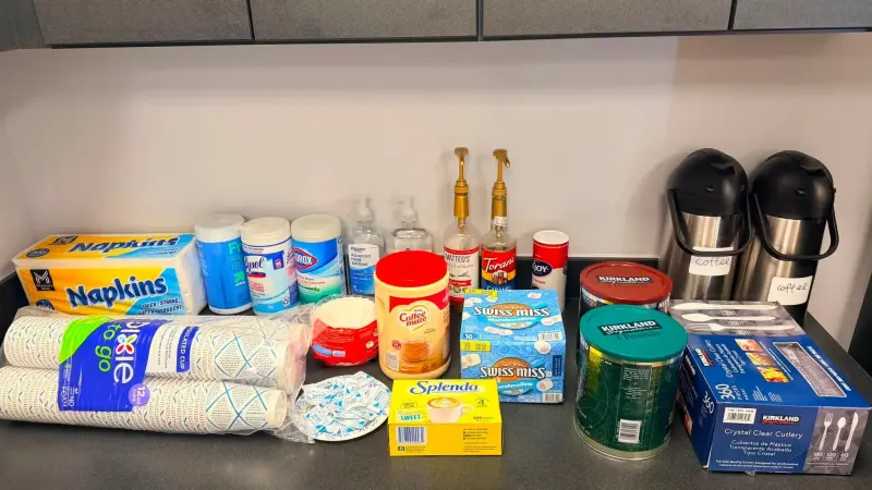 A lounge counter restocked with napkins, cups, coffee, cocoa, syrups and two full airpots