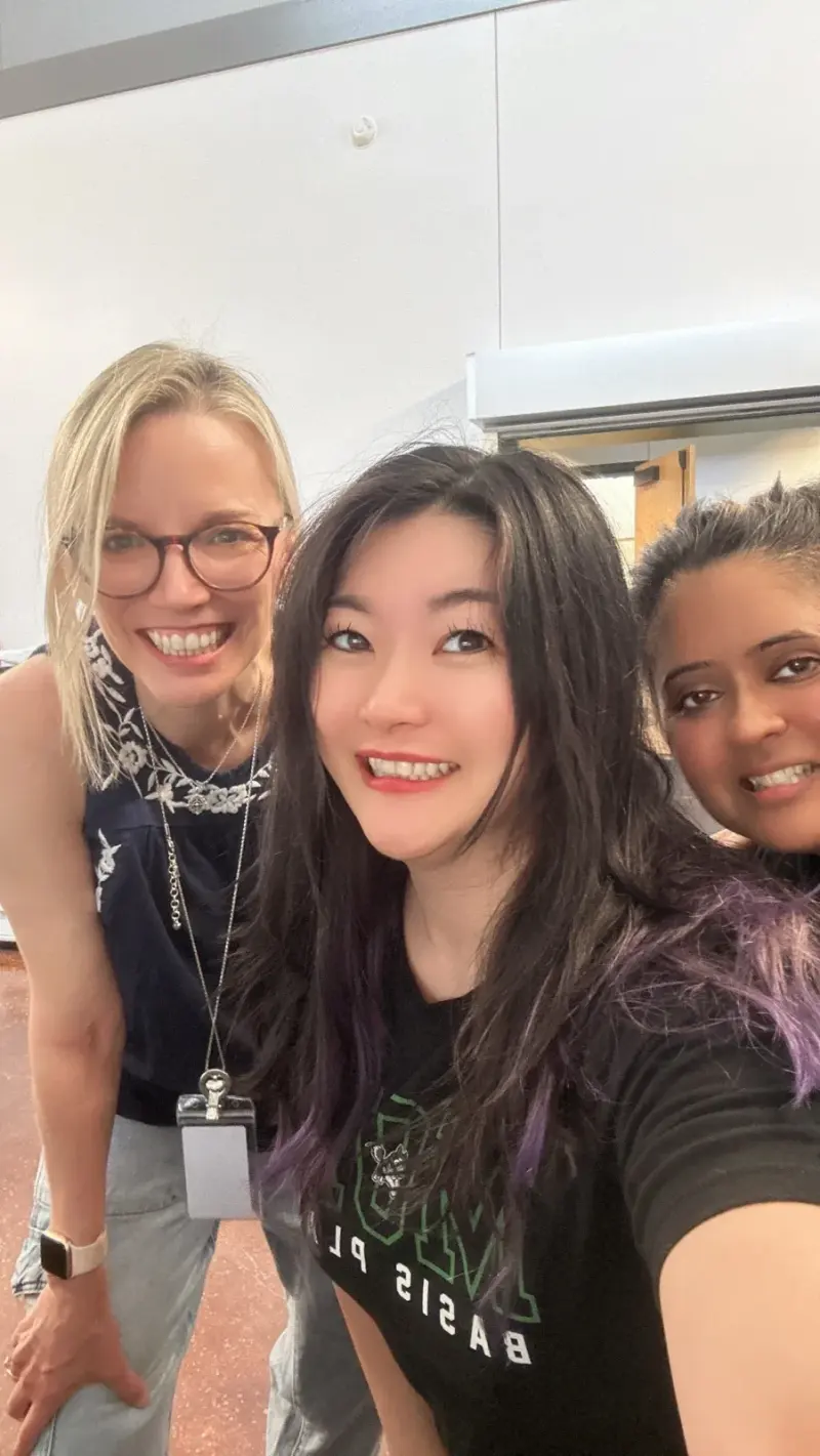 A selfie of three volunteers pausing in a classroom during the pre-opening work day