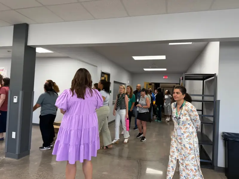 Staff heading back across the cafeteria after collecting lunch, one waving towards the camera