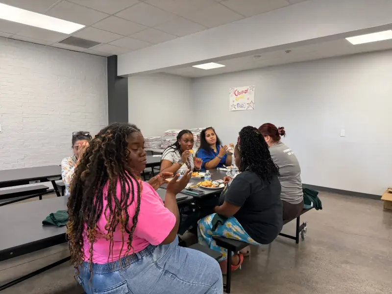 A group of staff sharing a table in the quieter side room, a “cheers” poster on the wall behind them