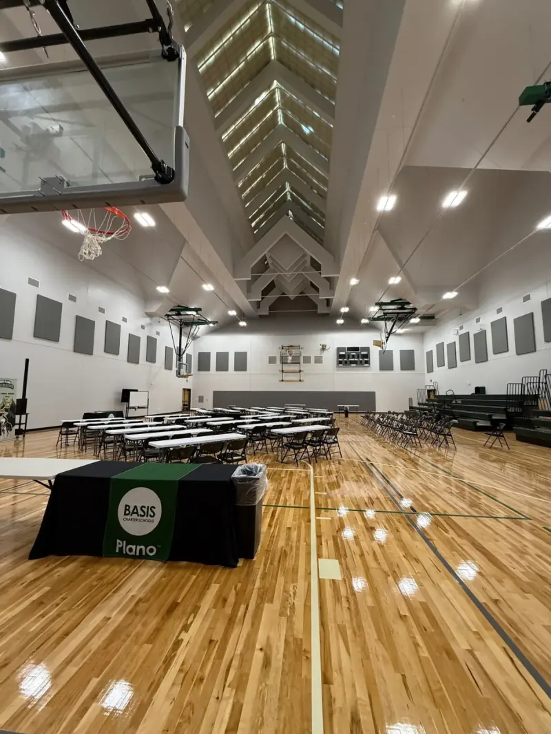The big gym set with long tables and chairs for an event, a BASIS Plano table cloth in the foreground