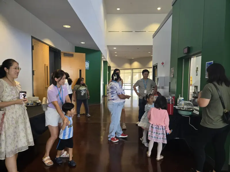 Families arriving through the lobby before the show, children gathering at the popcorn table along the green wall