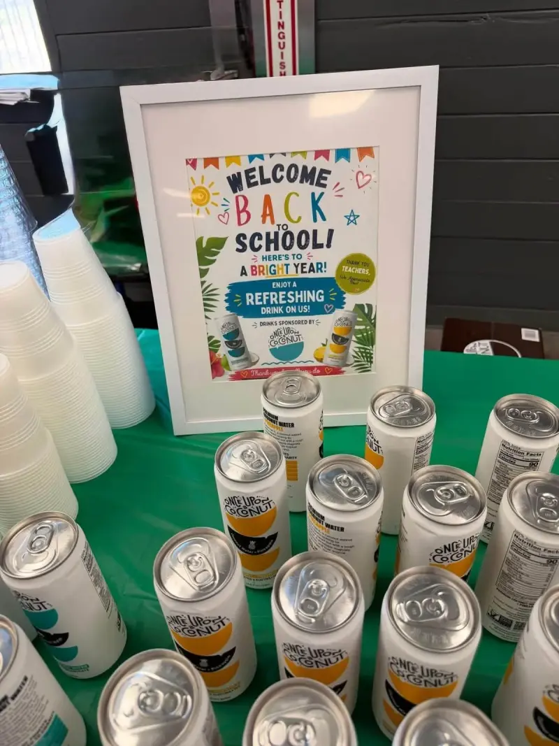 The framed drinks sign thanking the sponsor, seen close up over the tops of the cans