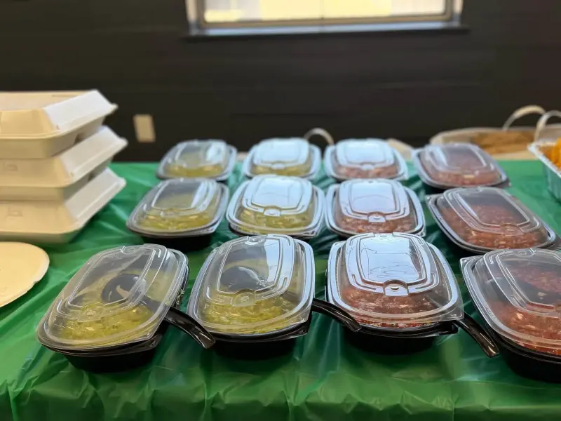 Fourteen lidded tubs of salsa, guacamole and beans set out in rows ready for the buffet
