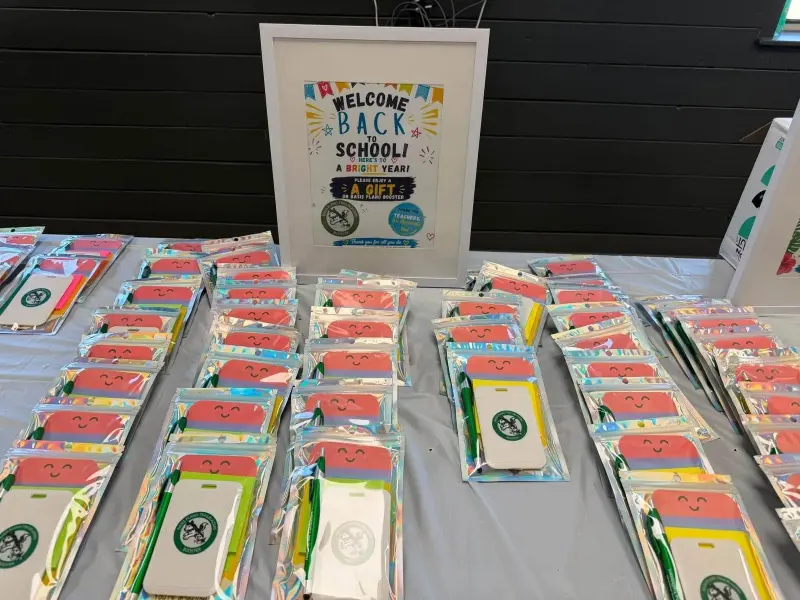 The gift packs close up, each holding a crest notebook, pen and coloured sticky notes, the welcome sign behind