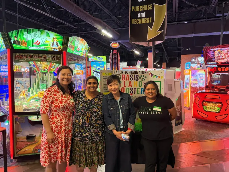 Four volunteers standing together beside the display board under the arcade’s “Purchase and Recharge” sign