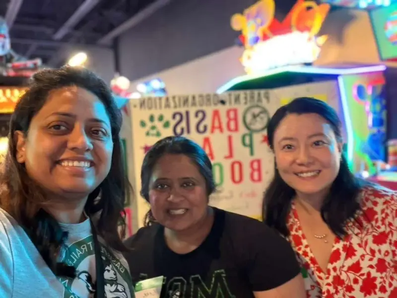 Three volunteers leaning in for a close selfie with the display board behind them