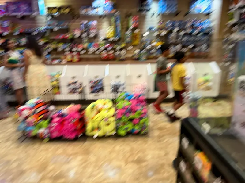 A blurred walk past the redemption shop, bins of brightly coloured plush prizes stacked along the floor