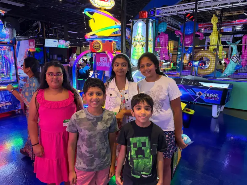 Five children posing together in the middle of the arcade, games and the climbing frame lit up behind them